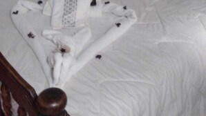Una cama bien hecha con edredón blanco y cabecera de madera.