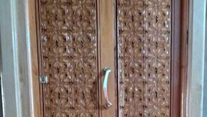 Una puerta de madera con tallas intrincadas y una placa con número.
