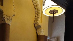 Un pasillo con columnas ornamentadas, baldosas de suelo estampadas y una pared con un collage de fotografías.