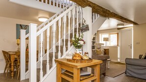 A staircase with white balusters leading to a landing. A wooden table with a vase of flowers and a sign reading "Half" is placed on the landing. - Railway Cottage: Cosy Cotswolds Farm Retreat (Evesham)