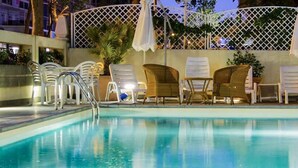 Une piscine entourée d’une clôture en treillis blanc, avec des chaises longues et des parasols.