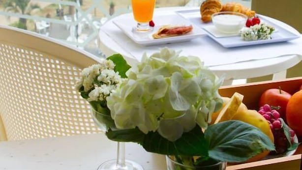 Un balcon avec une table dressée pour le petit-déjeuner, donnant sur une plage.