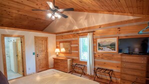 A wooden cabin bedroom with a bed, dresser, and a ceiling fan. - Firefly Fields | Minutes to Blue Ridge Parkway | Hot Tub & Screened Porch (Fleetwood)