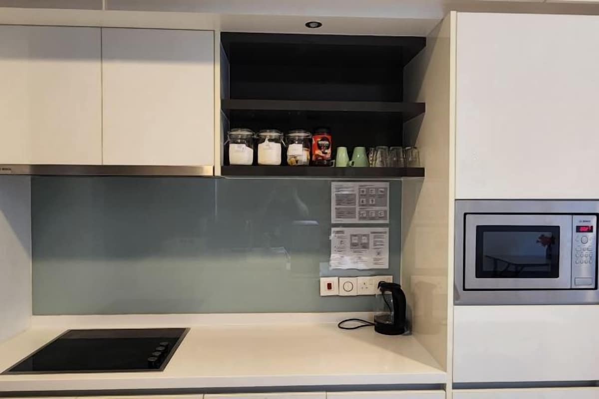 Una kitchenette equipada con microondas, cafetera y un pequeño estante con frascos.