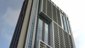 Un immeuble de grande hauteur doté d’une architecture moderne, caractérisé par une façade imposante ornée d’un motif en forme de grille et de grandes fenêtres.