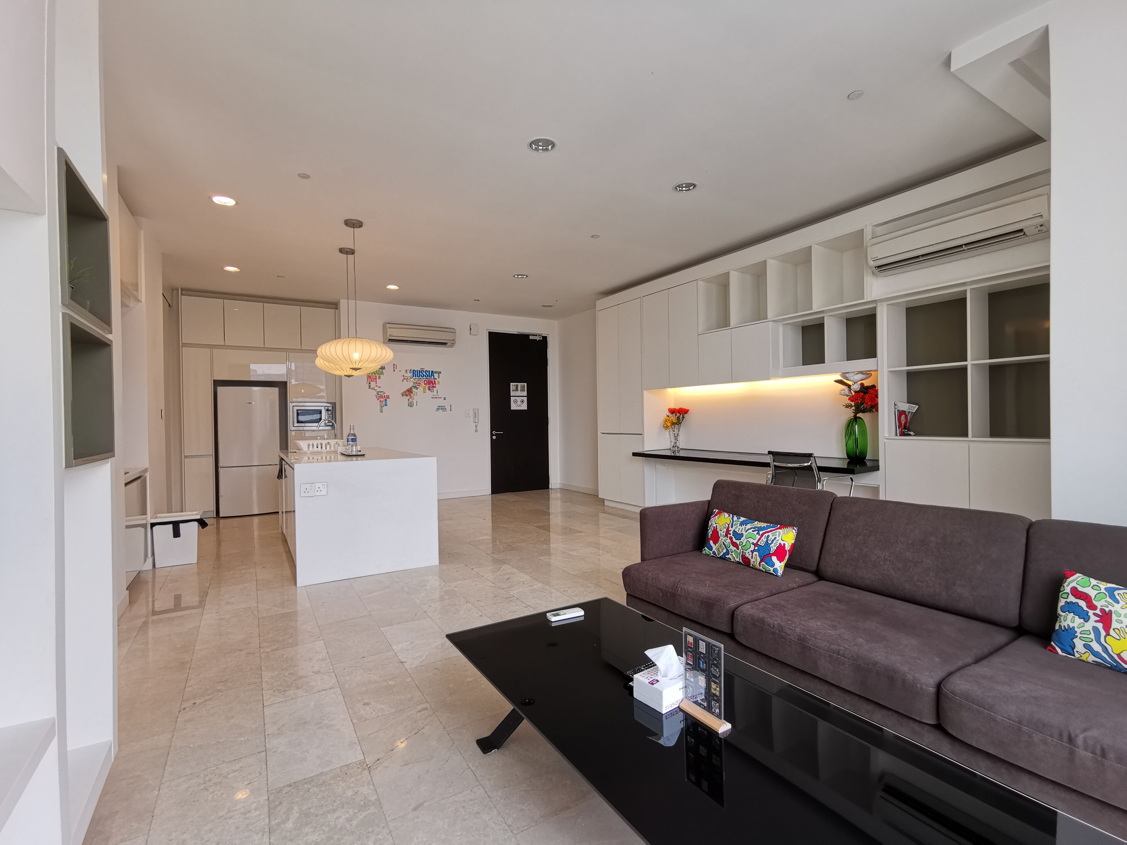 A modern living room with a sofa, a coffee table, and a kitchen area in the background.