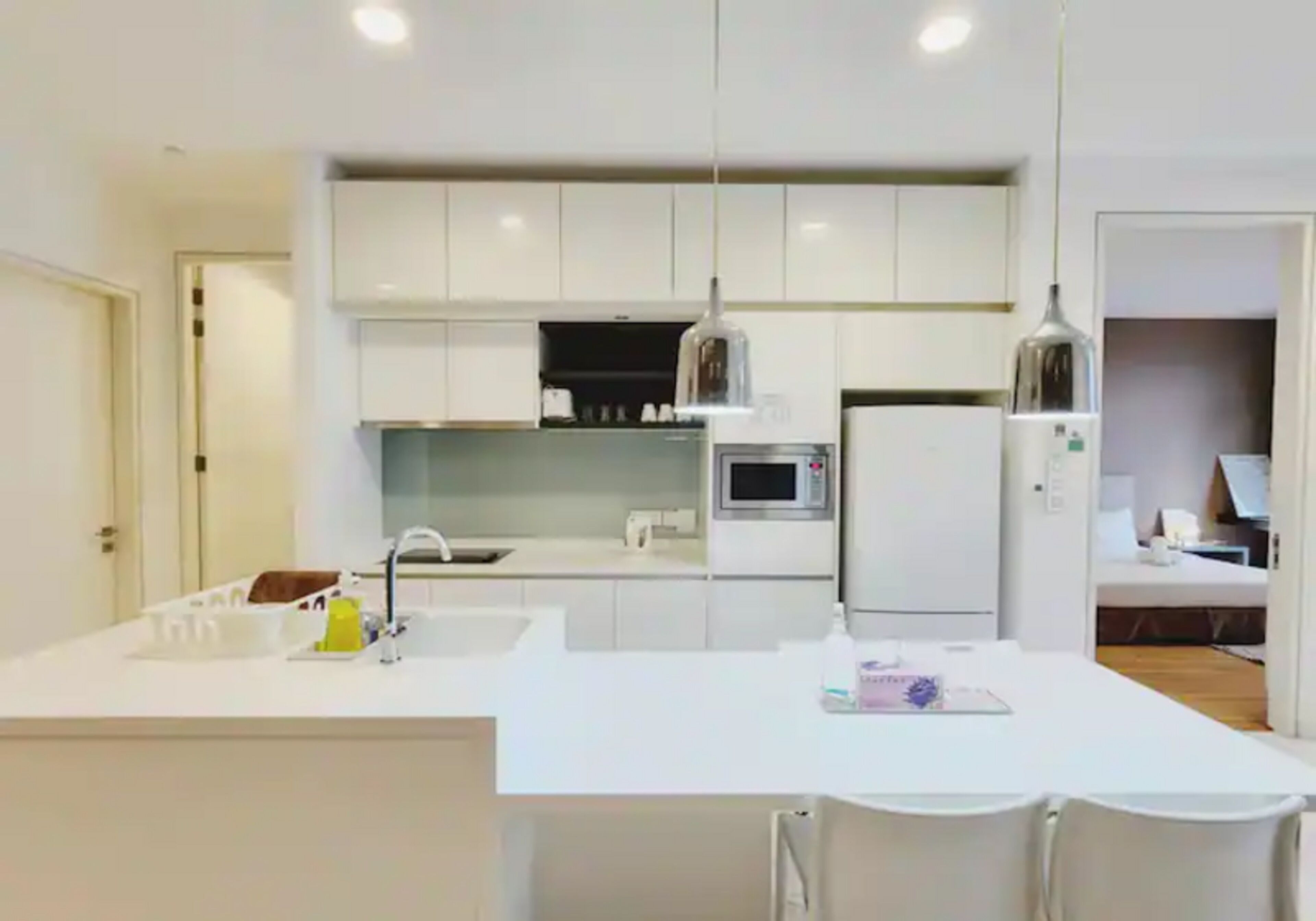 Una cocina moderna con armarios blancos, una isla central e iluminación colgante.