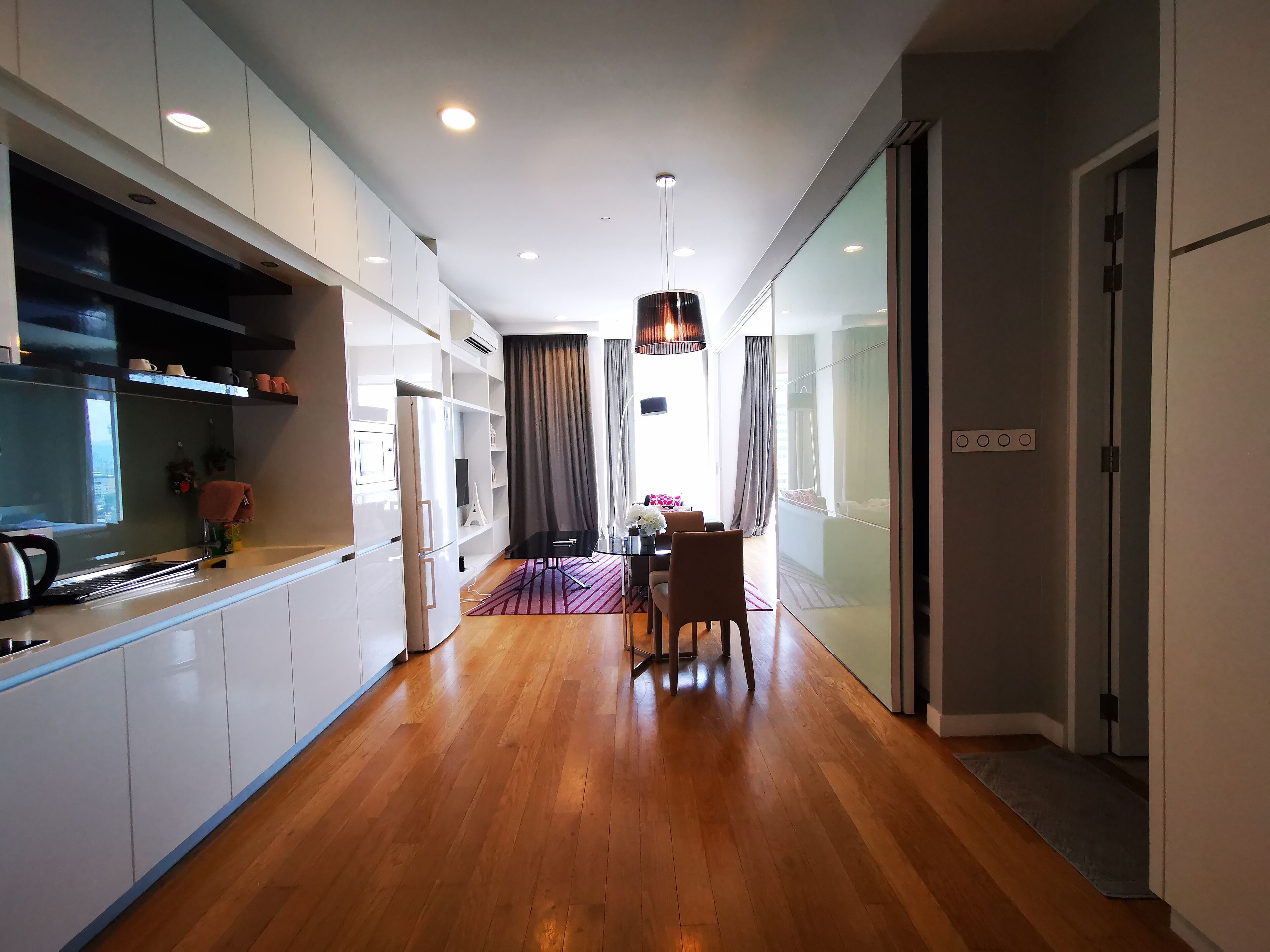 Eine moderne Küche mit weißen Schränken, einer Holzausziehtafel und einem Essbereich mit Tisch und Stühlen.