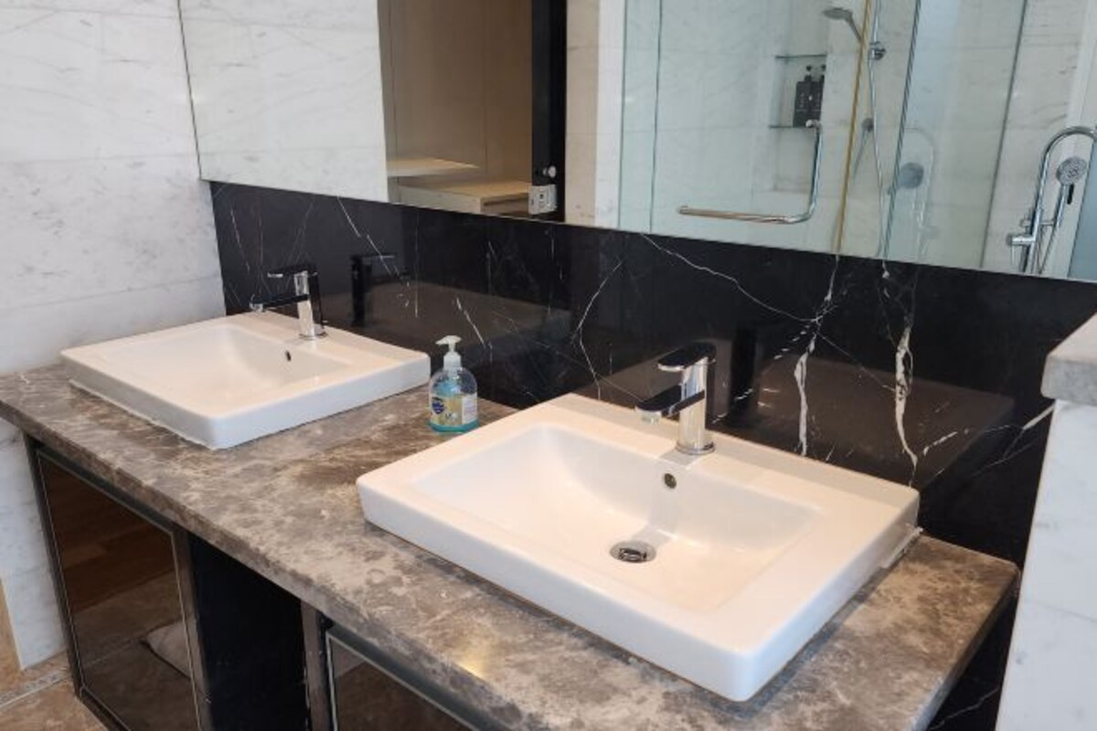 Een badkamer met twee witte wastafels, een spiegel en een douchehoek.