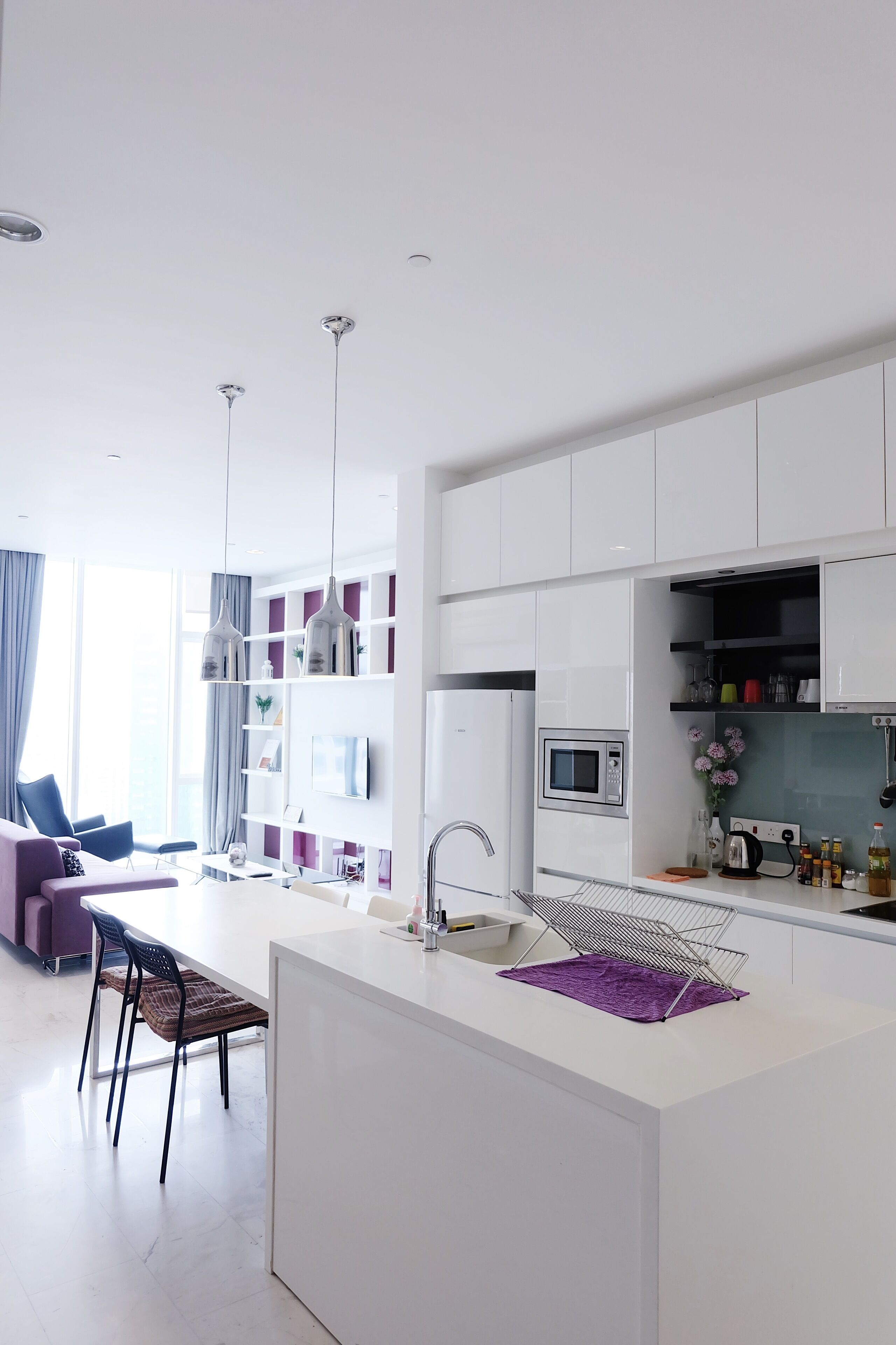 A modern kitchen with white cabinetry, a central island, and pendant lighting.