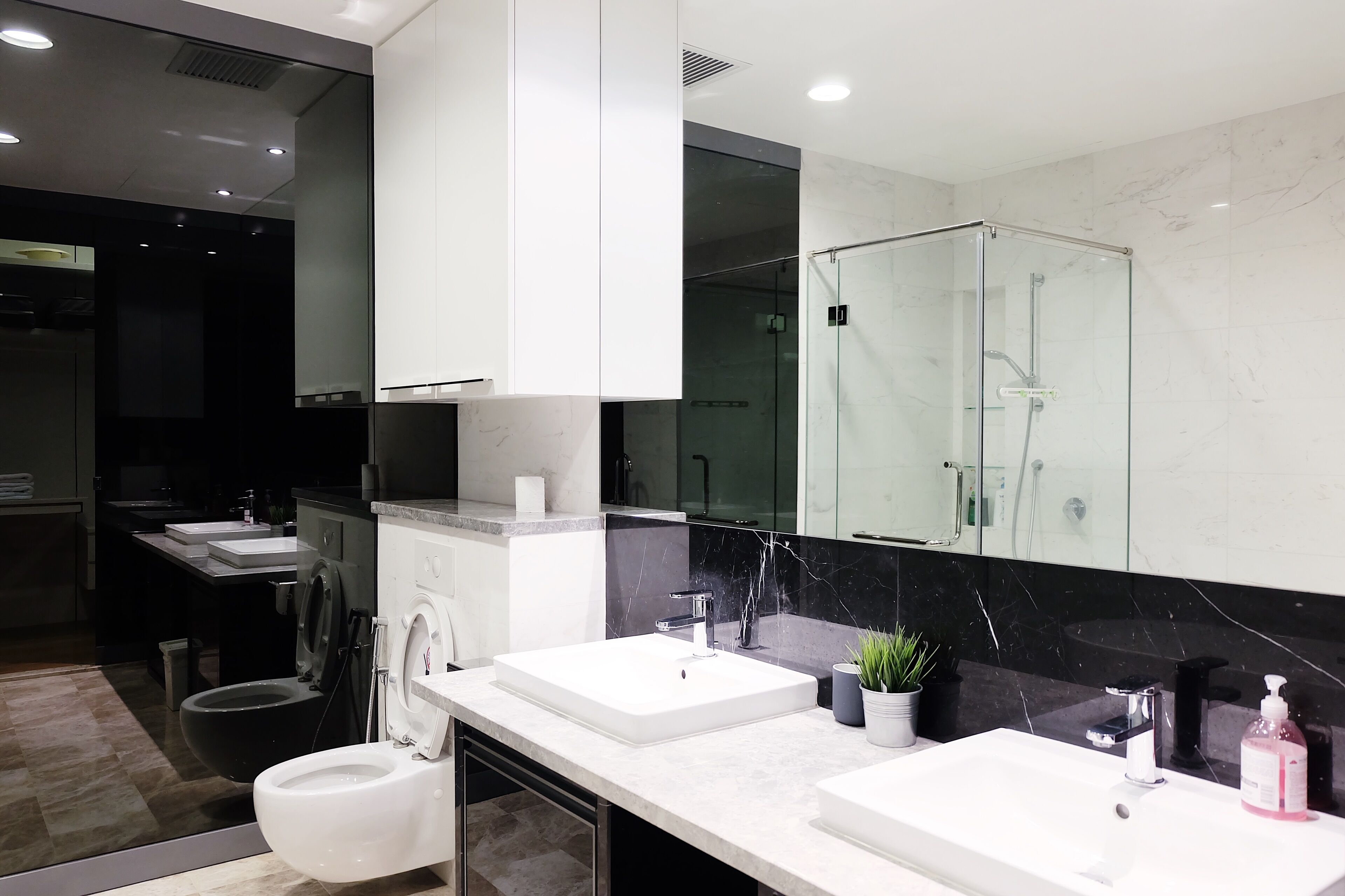A modern bathroom with two sinks, a toilet, and a glass-enclosed shower.