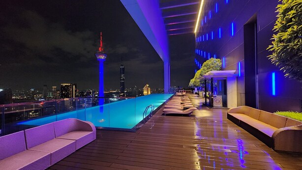 Un espace piscine aménagé sur le toit, offrant une vue panoramique sur la ville, avec notamment une tour imposante.