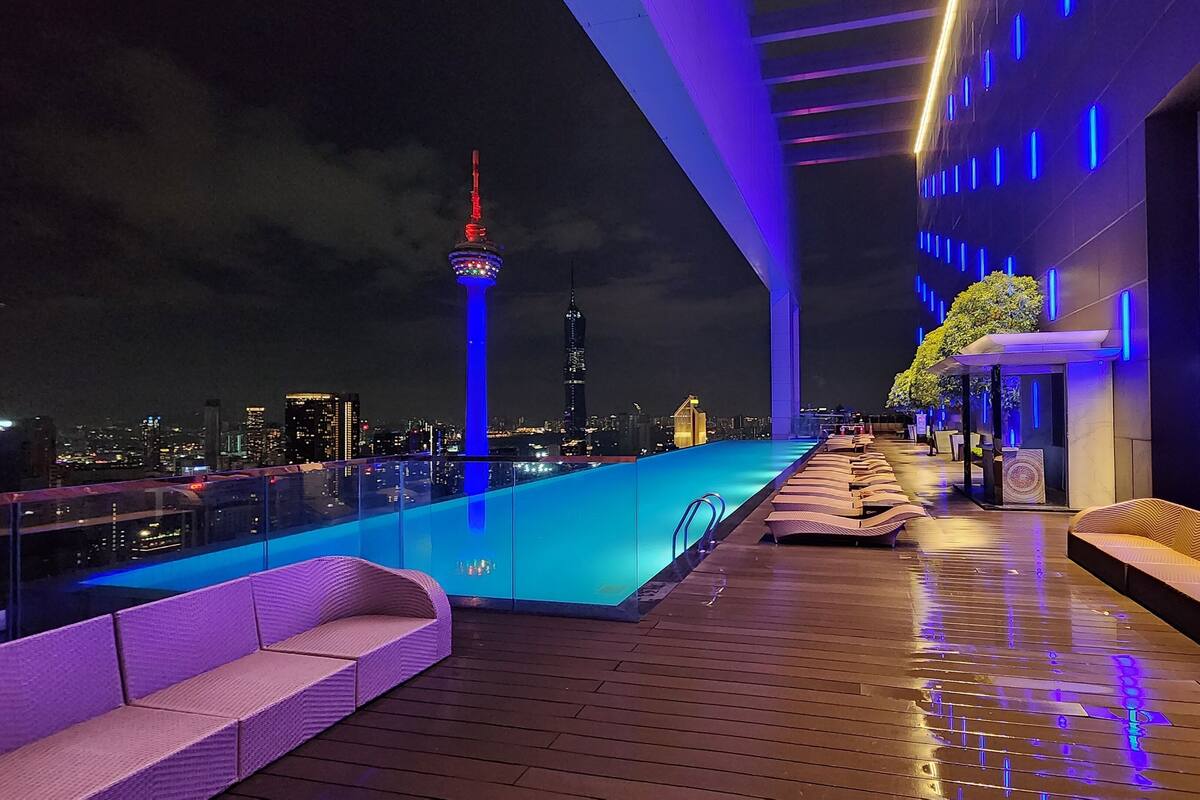 Un espace piscine aménagé sur le toit, offrant une vue panoramique sur la ville, avec notamment une tour imposante.