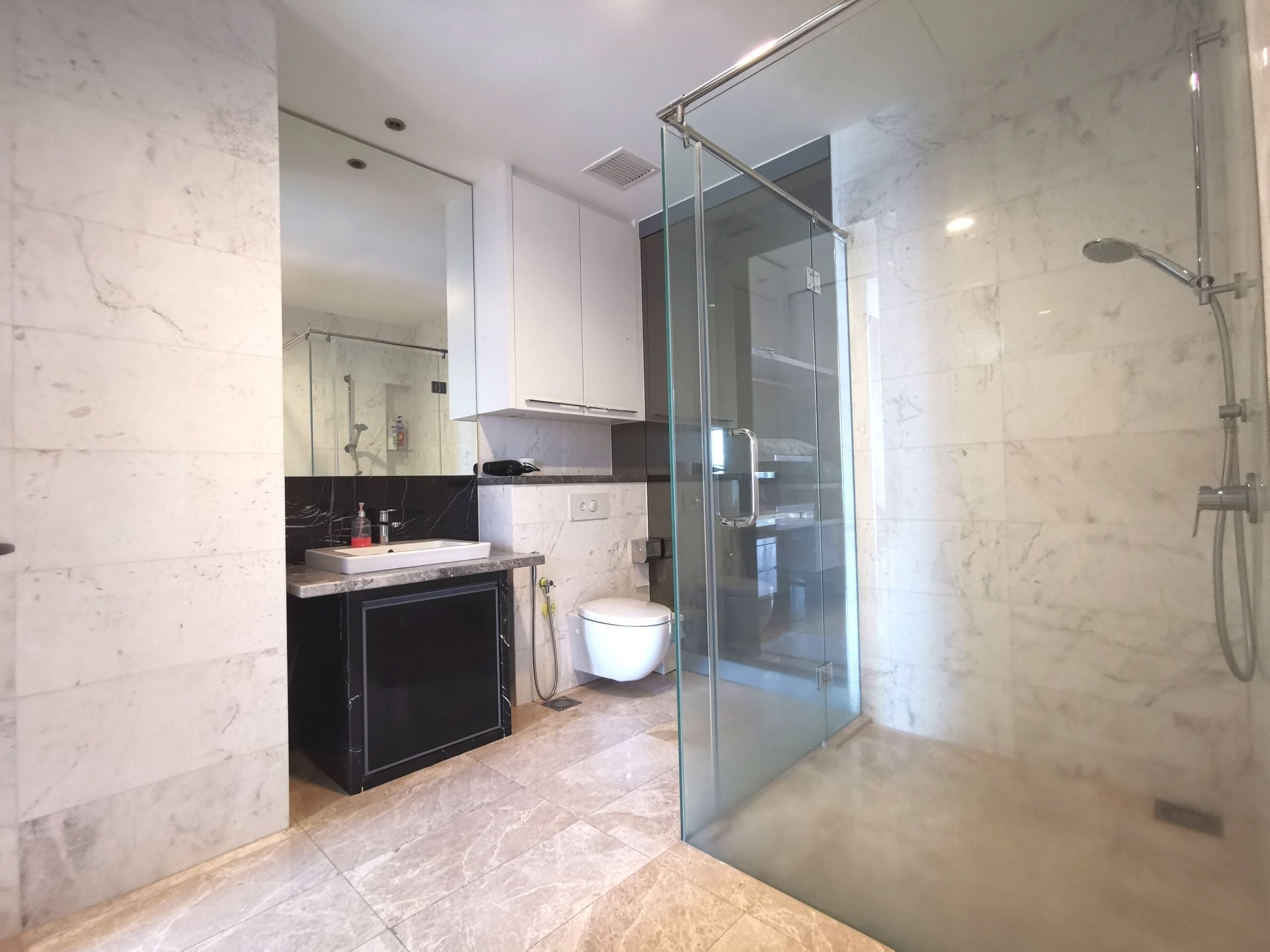 A modern bathroom with a glass-enclosed shower, a white toilet, and a black vanity.