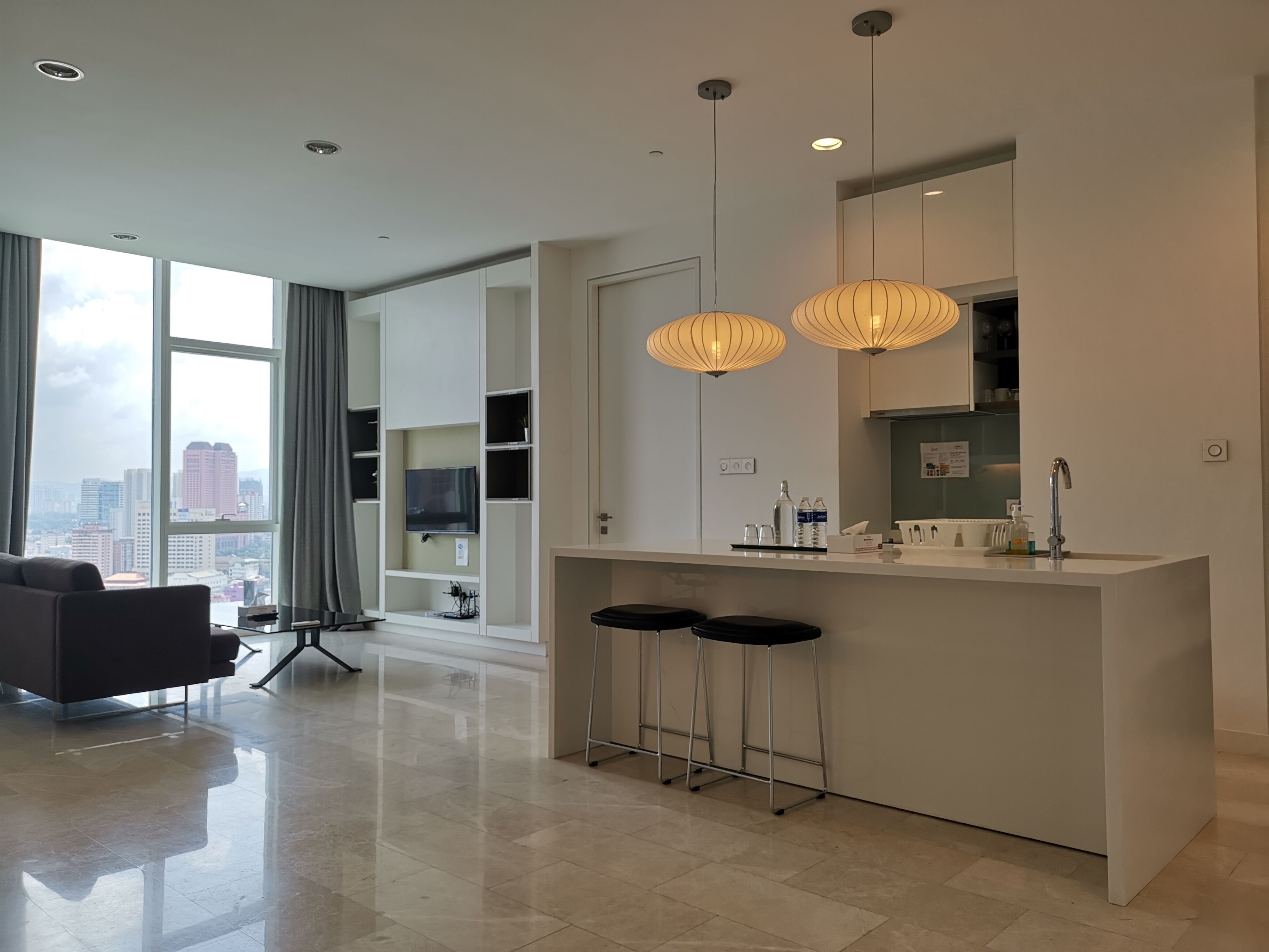 A modern kitchen with a bar area, large windows, and a city view.