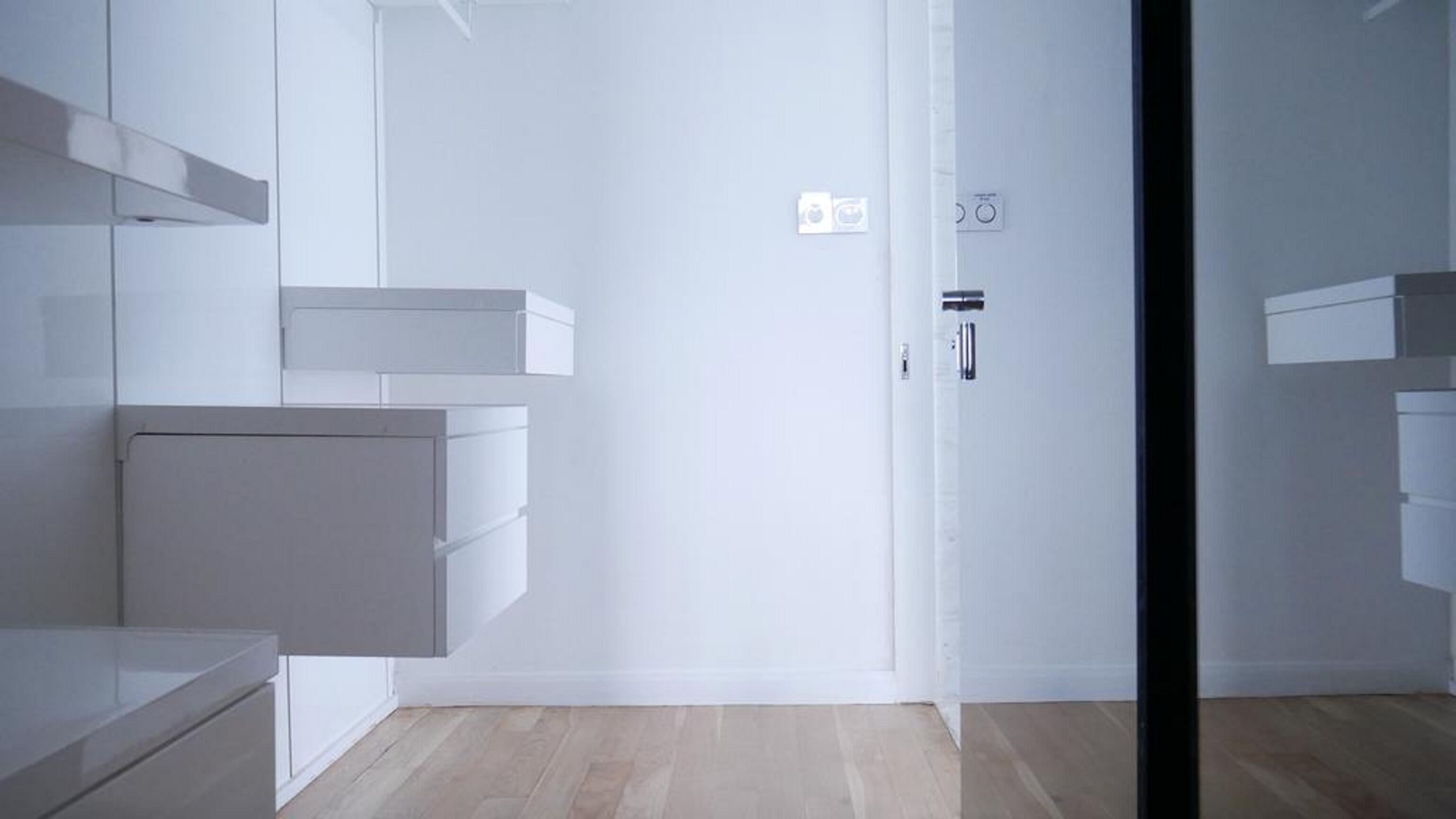 Une salle de bain moderne et minimaliste, dotée d’un grand miroir, d’un lavabo encastré et d’un espace douche.
