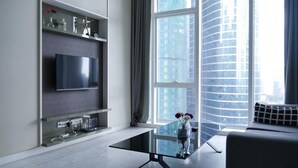 Un salon moderne avec un téléviseur à écran plat, une table basse en verre et un canapé.