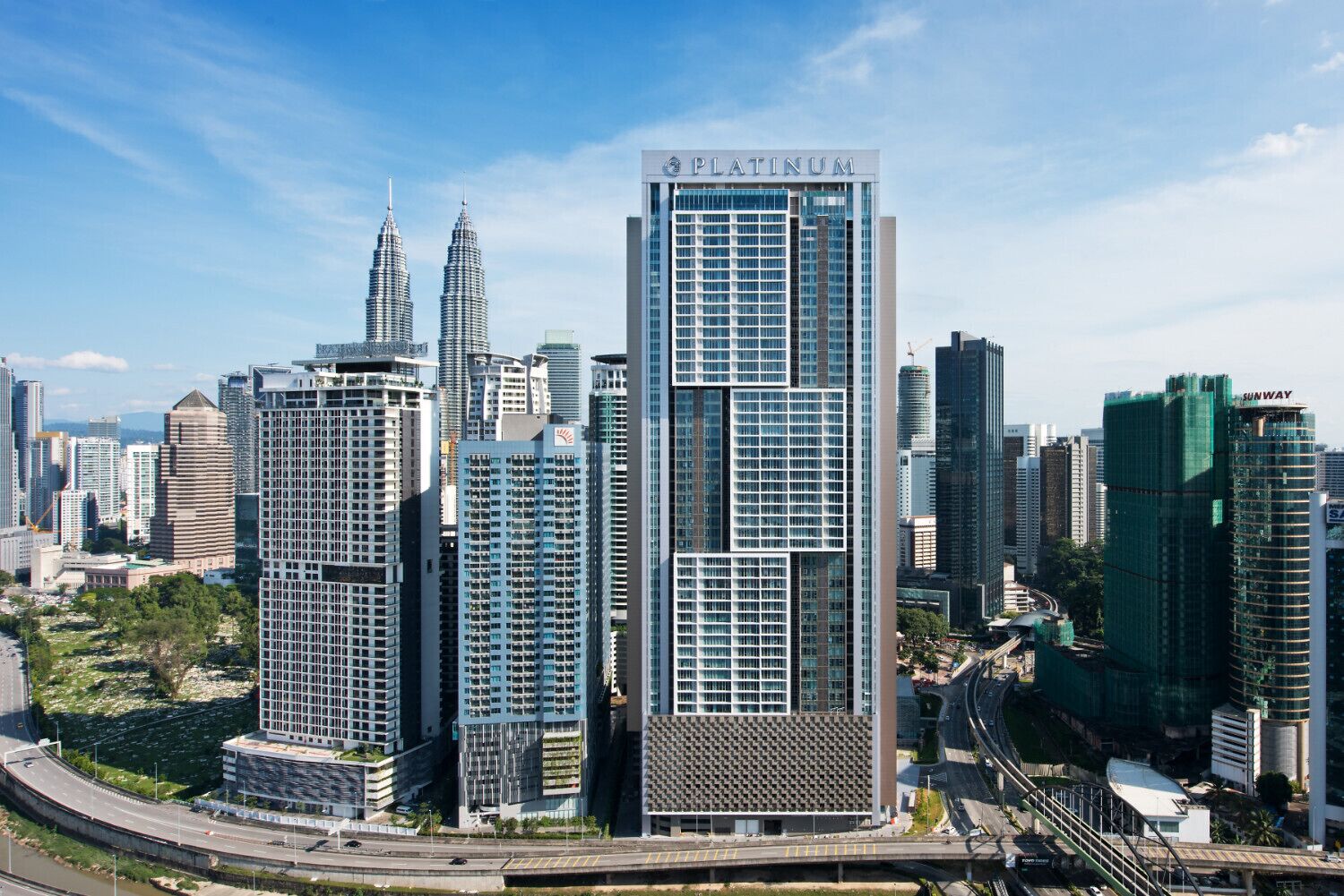 A modern high-rise building with a prominent 'Platinum' sign, surrounded by other high-rise buildings in a cityscape.