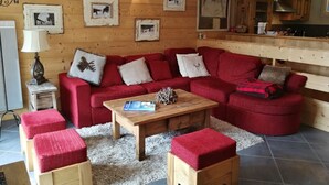 Una sala de estar acogedora con un sofá rojo, una mesa de centro de madera y una chimenea.