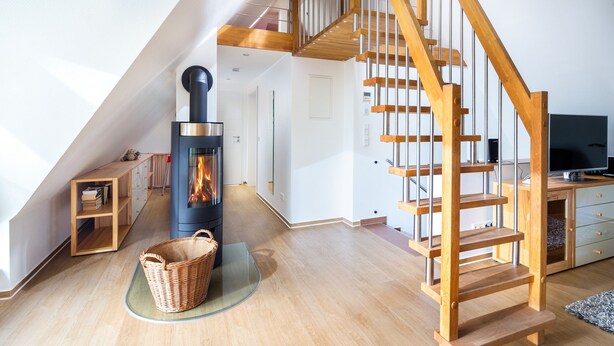 Una sala moderna con escalera de madera, chimenea y televisor.