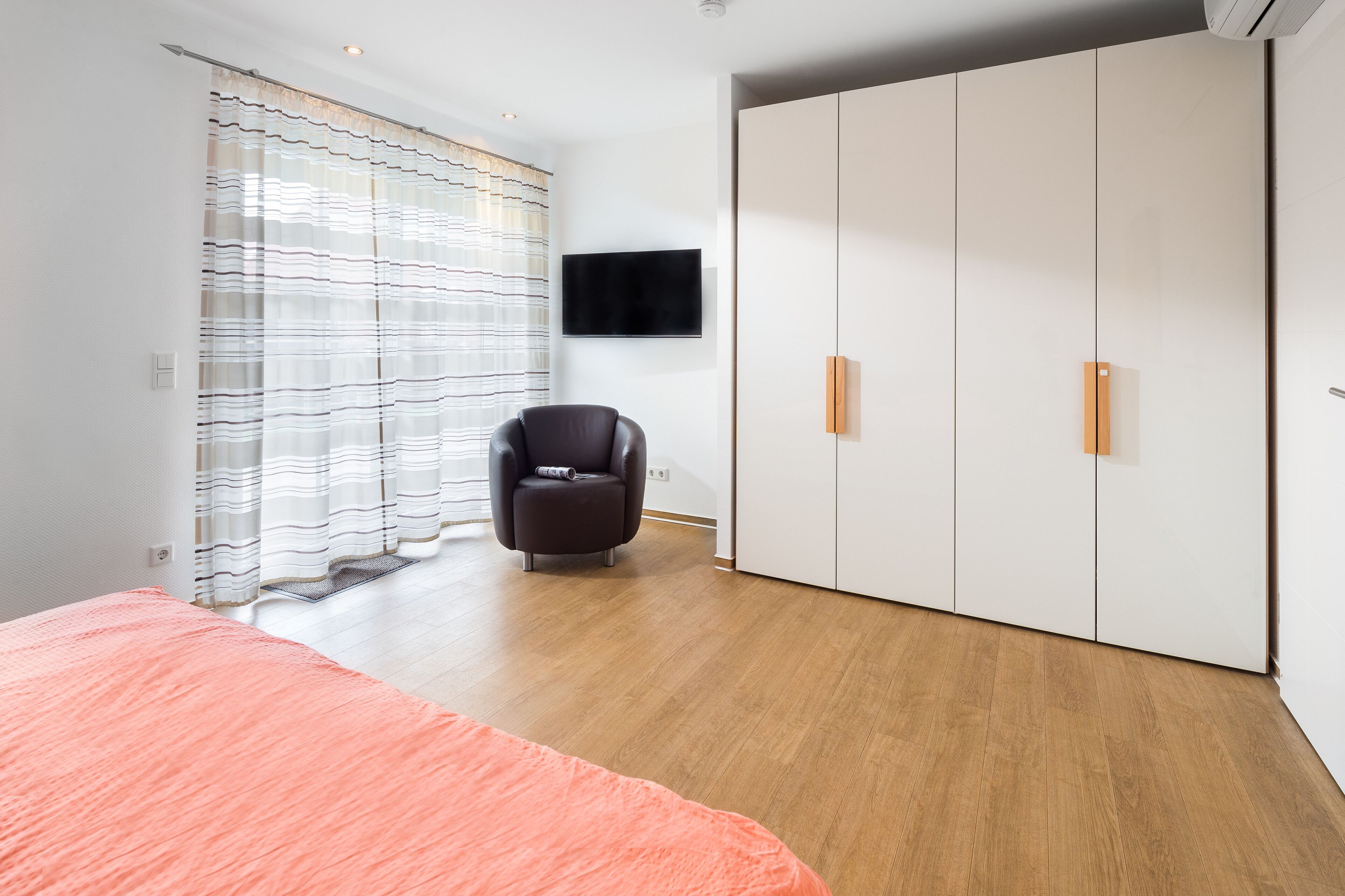 Une chambre à coucher avec un lit, une chaise, une armoire et un téléviseur.