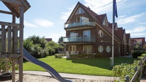 Una casa de dos pisos con balcón, tobogán y una bandera.