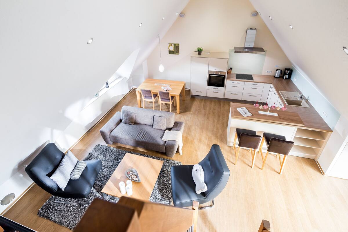 A modern loft apartment with a dining area, kitchen, and living space.