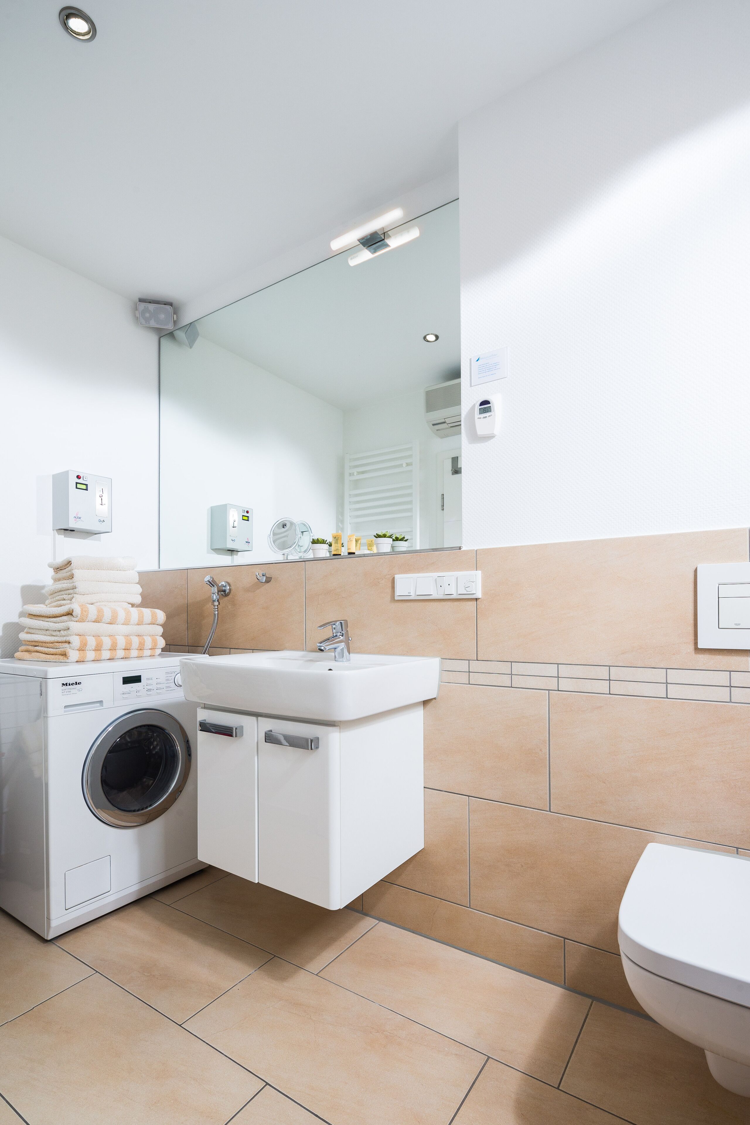 Un baño moderno con lavadora, lavamanos y retrete.