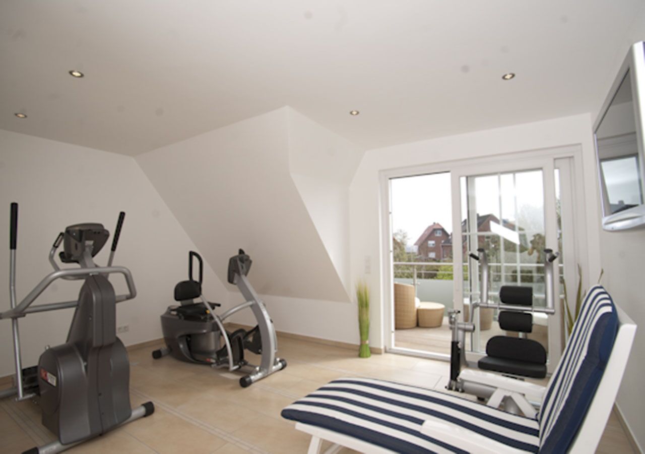 A home gym with exercise equipment, a large window, and a view of the outside.