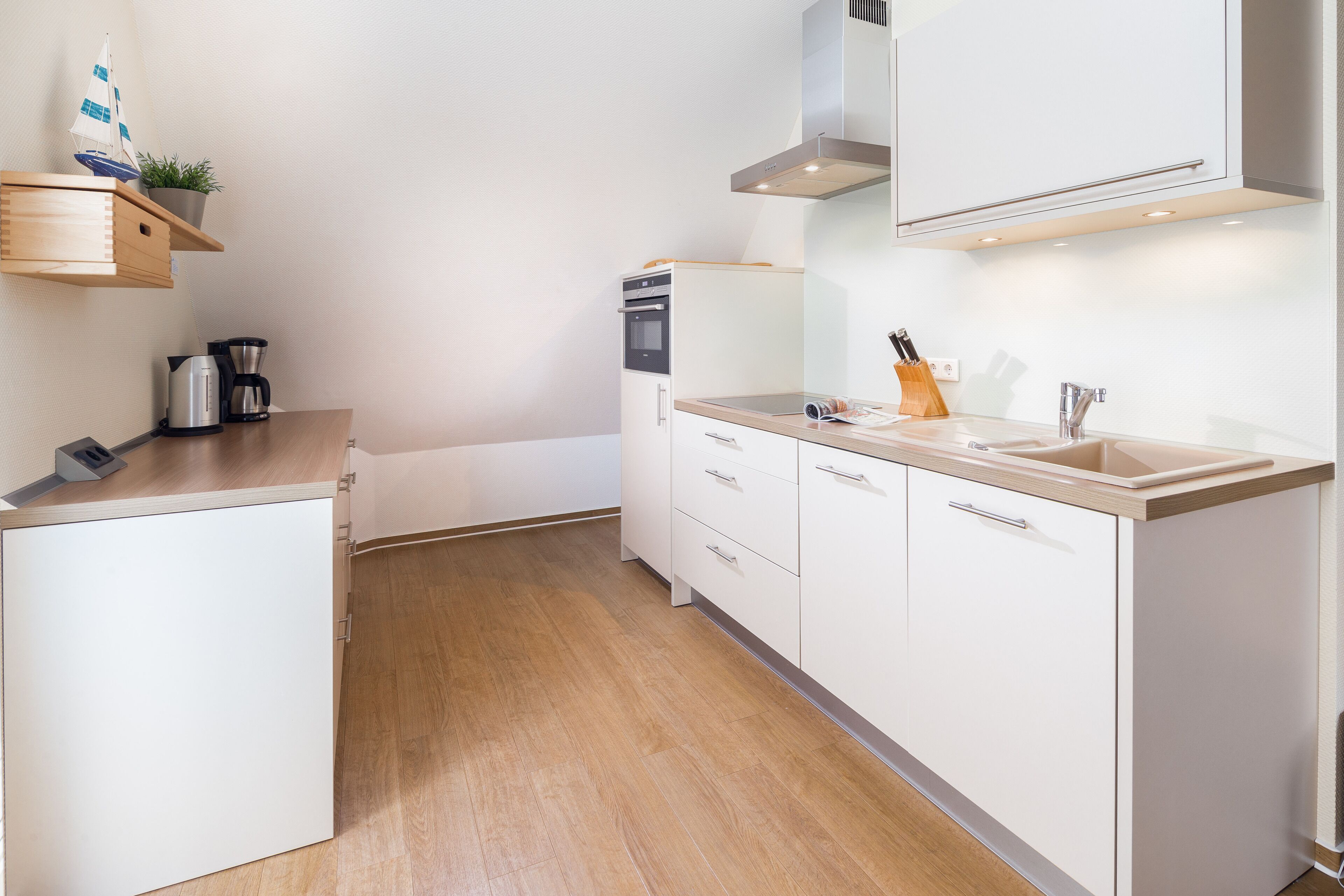 A modern kitchen with white cabinetry, a wooden countertop, and a built-in oven.