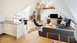 Un loft moderno con cocina, comedor y sala de estar. Cuenta con una cama en loft, una escalera y un gran ventanal que proporciona luz natural.