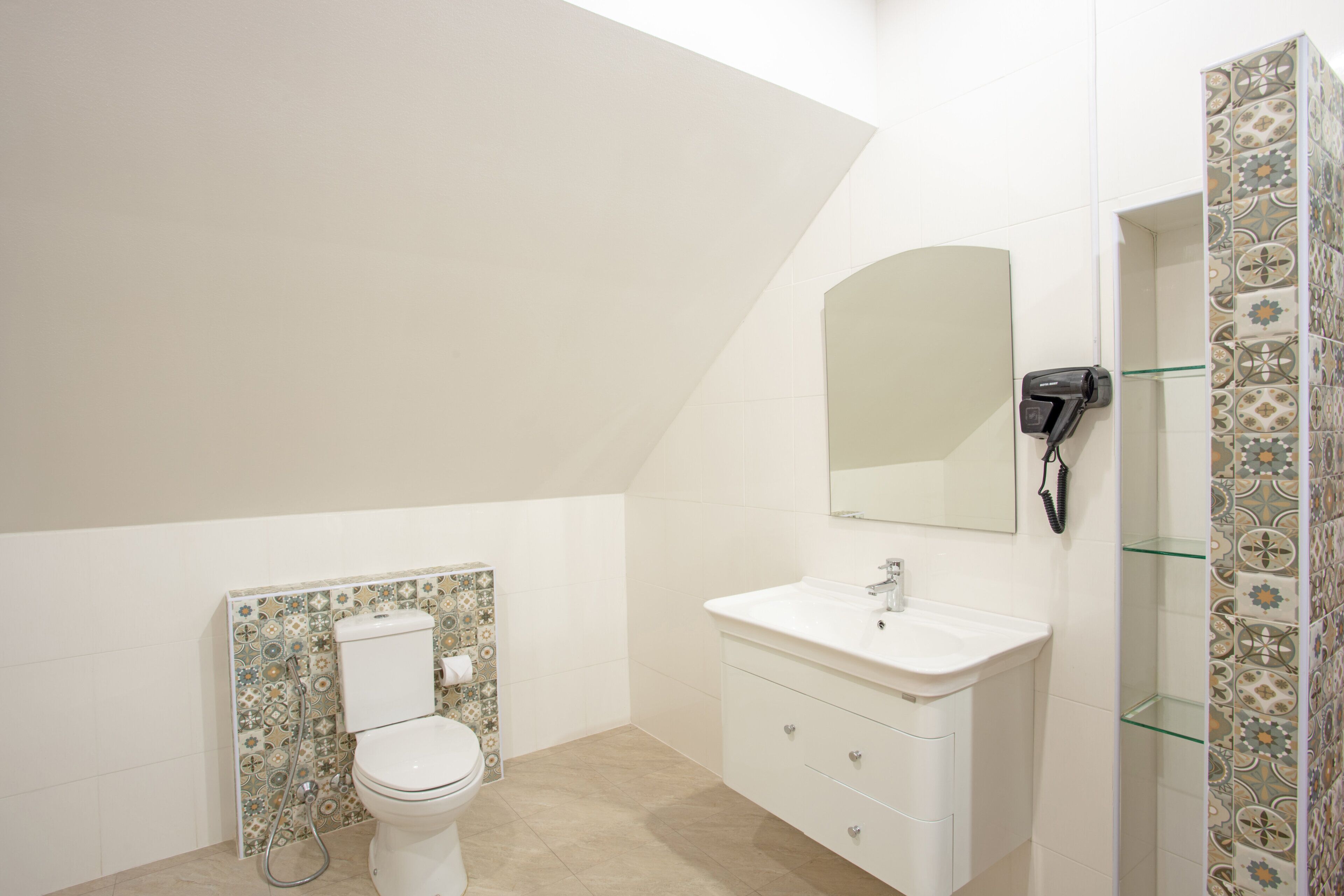 Ein Badezimmer mit Toilette, Waschbecken, Spiegel und Duschbereich.