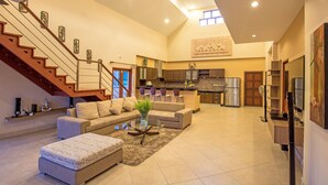 A spacious living area with a staircase, a sofa set, a coffee table, and a kitchen in the background. - Blissful Villa Felicity with Ample Space (Rawai)