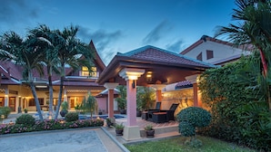 A hotel with a covered outdoor seating area, palm trees, and a well-maintained garden. - Blissful Villa Felicity with Ample Space (Rawai)