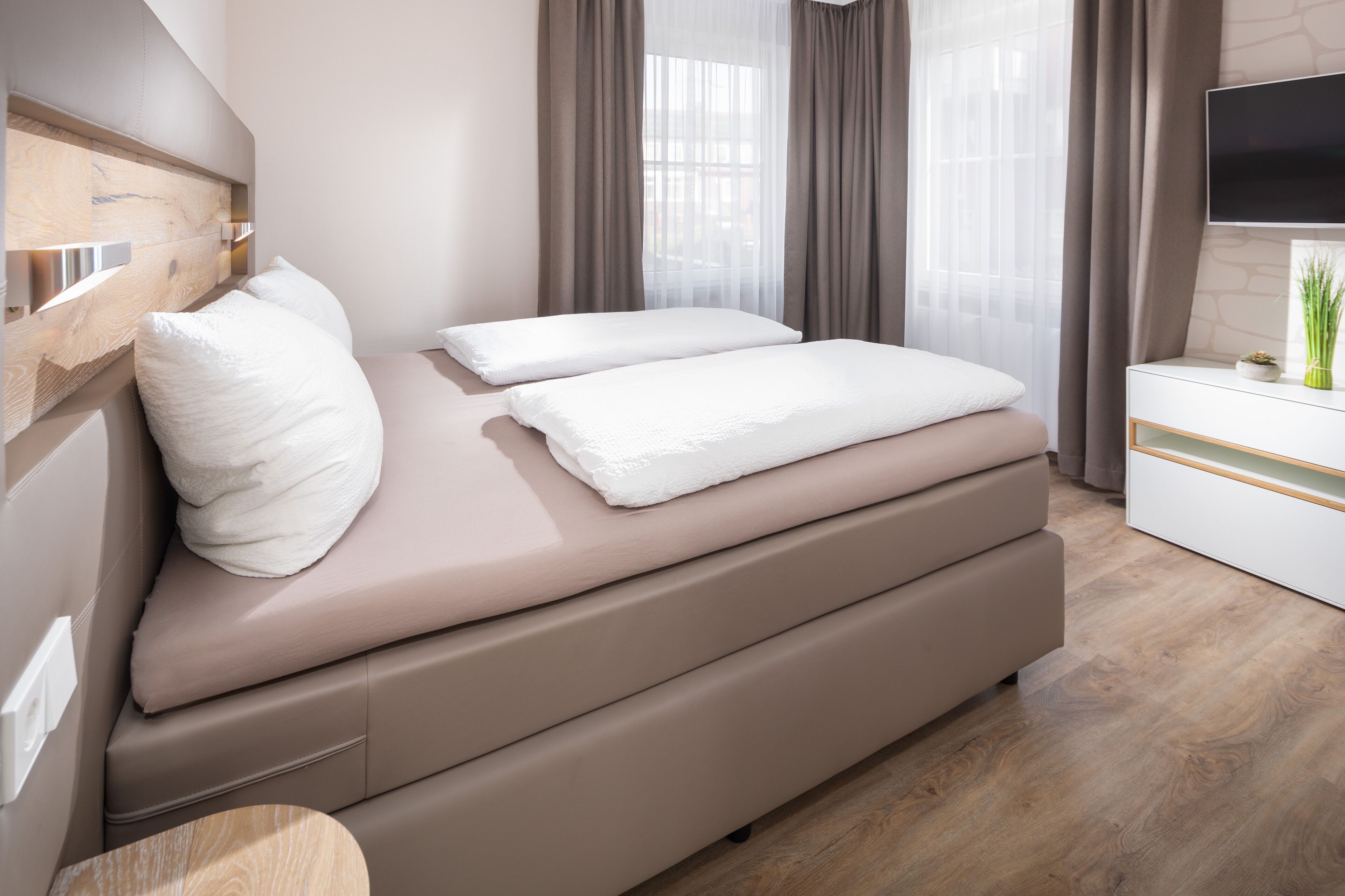 Een moderne slaapkamer met een bed, nachtkastje en televisie.