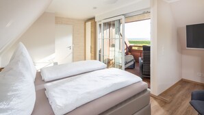 A bedroom with a bed, a TV, and a balcony with a view. - Winkelschiffchen II (Juist)