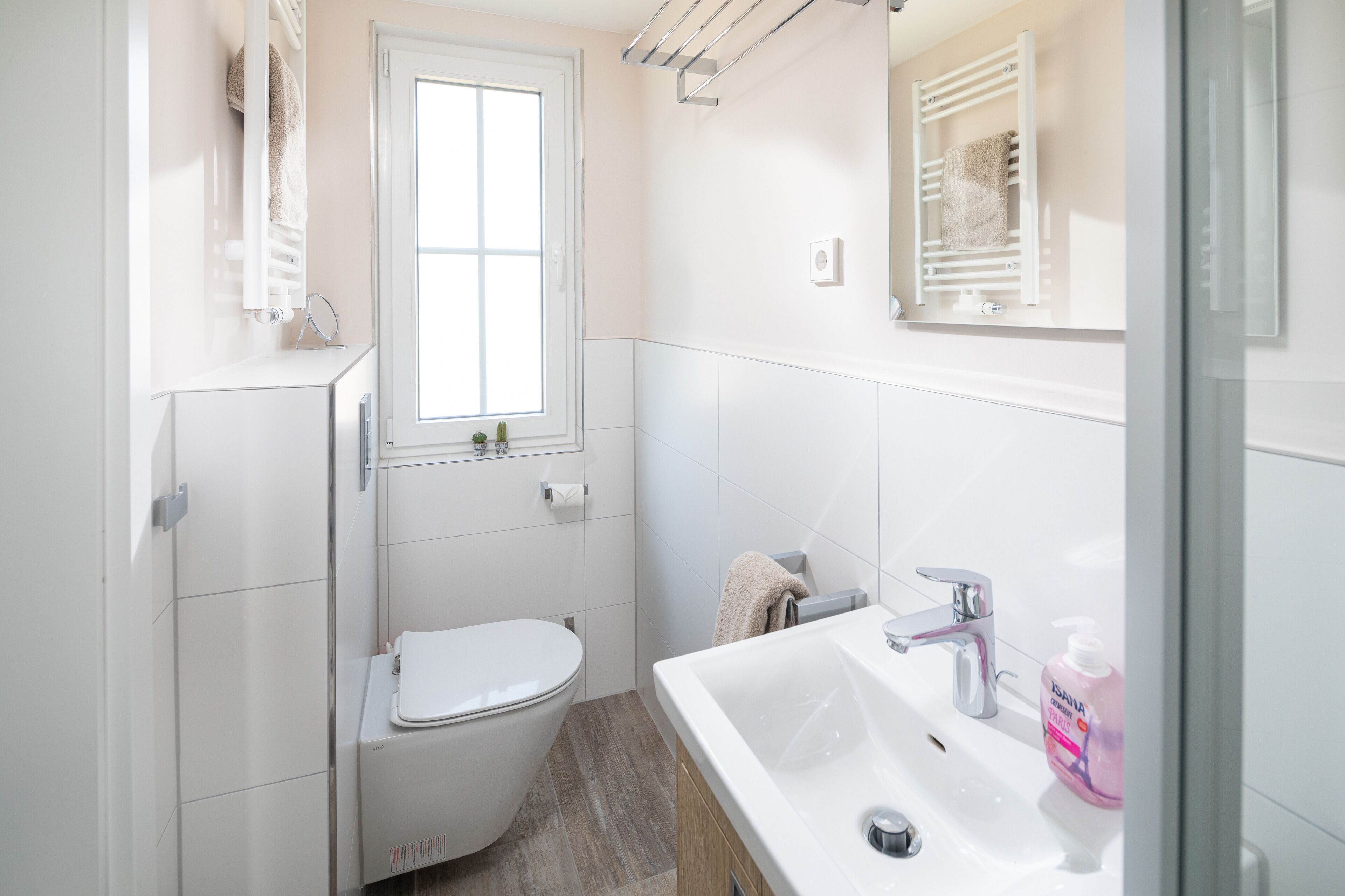 A modern bathroom with a toilet, sink, and towel rack.