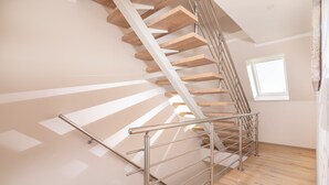 A modern staircase with wooden steps and metal railings, leading to an upper floor. - Winkelschiffchen II (Juist)