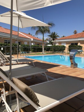 Ein Poolbereich mit Liegestühlen, einem Pool und einem Gebäude mit einem Ziegeldach.