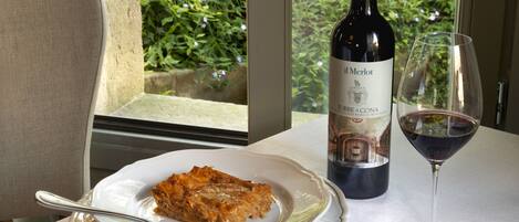 A table with a plate of food, a wine bottle, and a wine glass.