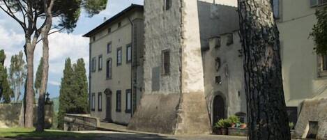 A historic building with a tower, surrounded by trees and a well-maintained lawn.