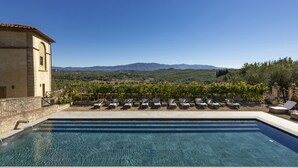 Une piscine dotée de chaises longues et offrant une vue sur les vignobles et les montagnes.