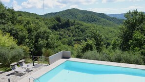 A swimming pool with lounge chairs and a view of a forested mountain. - Villa con Piscina - Il Paradiso Assisi (Assisi)