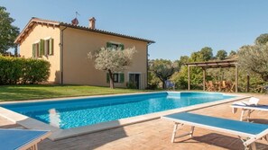 A house with a swimming pool, a pergola, and a garden.