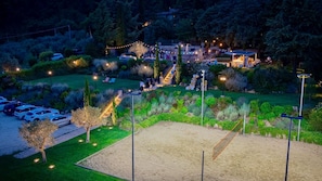 A landscaped outdoor area with a sandy play area, a staircase, and a building with string lights.