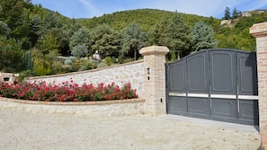 A gated entrance with a stone wall and a gravel driveway.