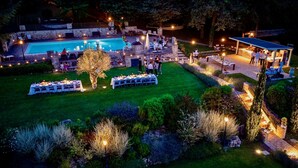 Un événement en plein air avec une piscine, des tables dressées pour le repas et un espace couvert où se trouvent des personnes.