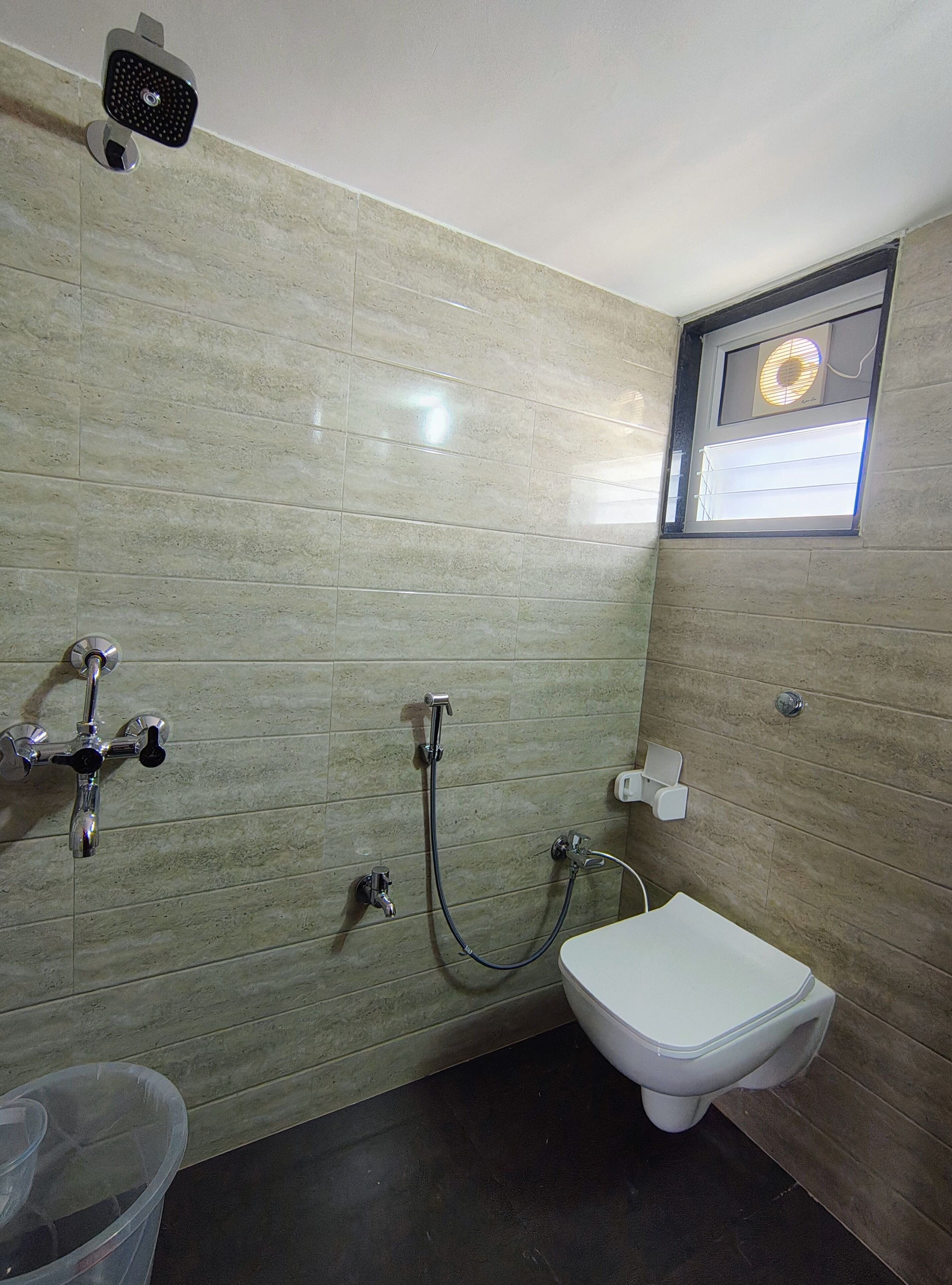 Un baño con inodoro, ducha y calentador de pared.