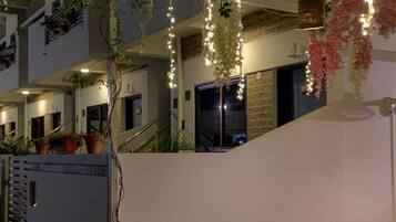 Ein Außenbereich mit einer Terrasse, einem Esstisch, Stühlen, Lichterketten und Topfpflanzen.