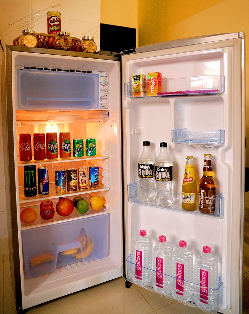 An open refrigerator with various beverages and fruits.